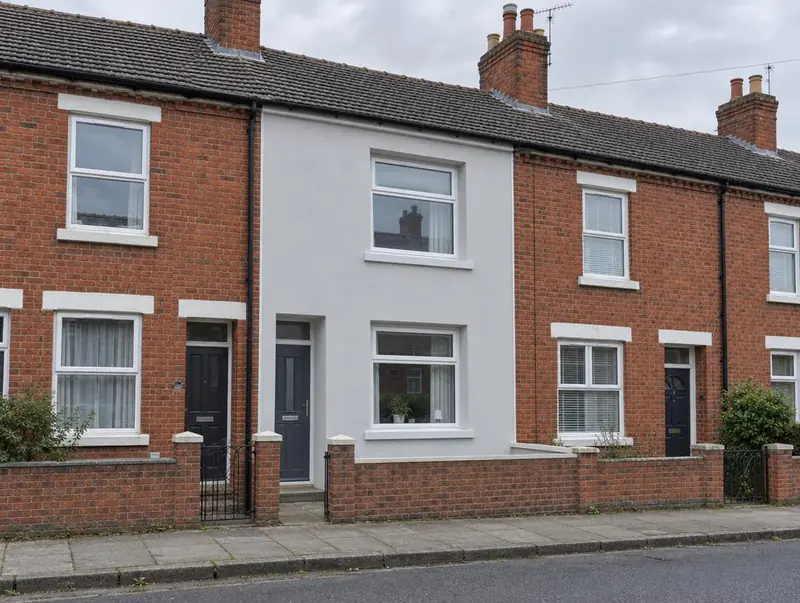 Mid-terrace house finished in pale grey insulated render between red brick neighbours